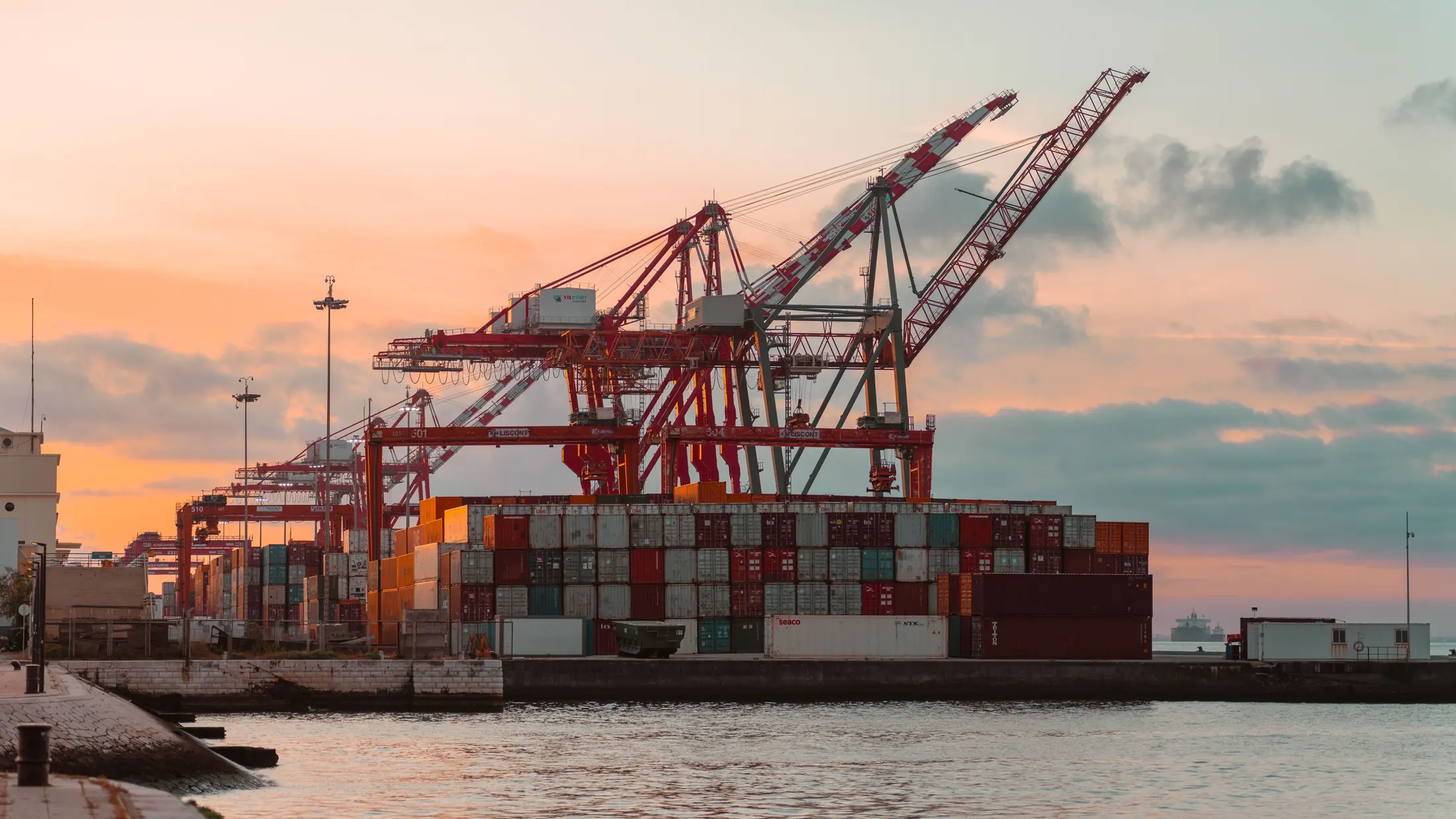 Ship-to-shore cranes over stacked containers at sunrise