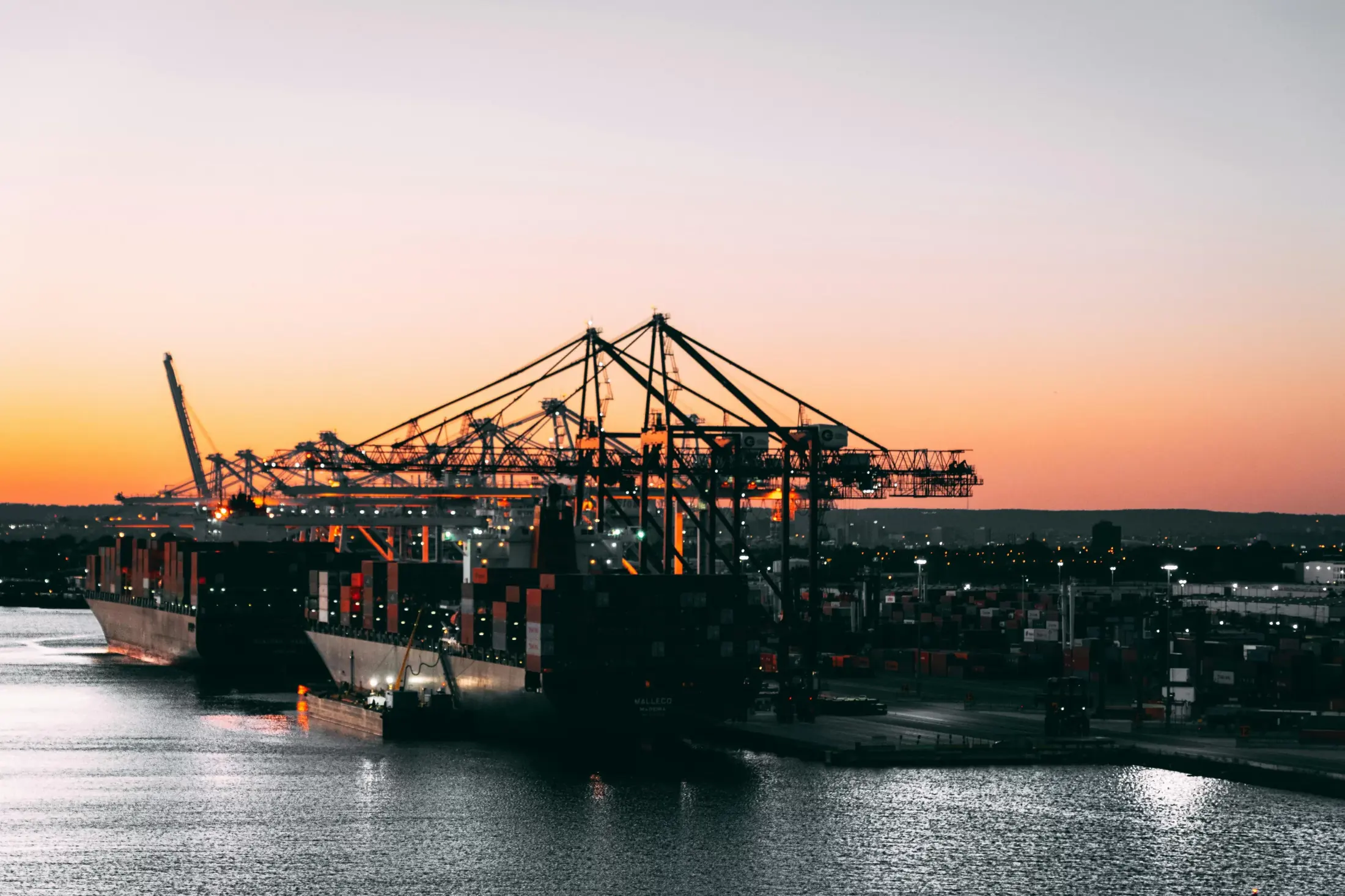 Container terminal cranes silhouetted against a dusk sky